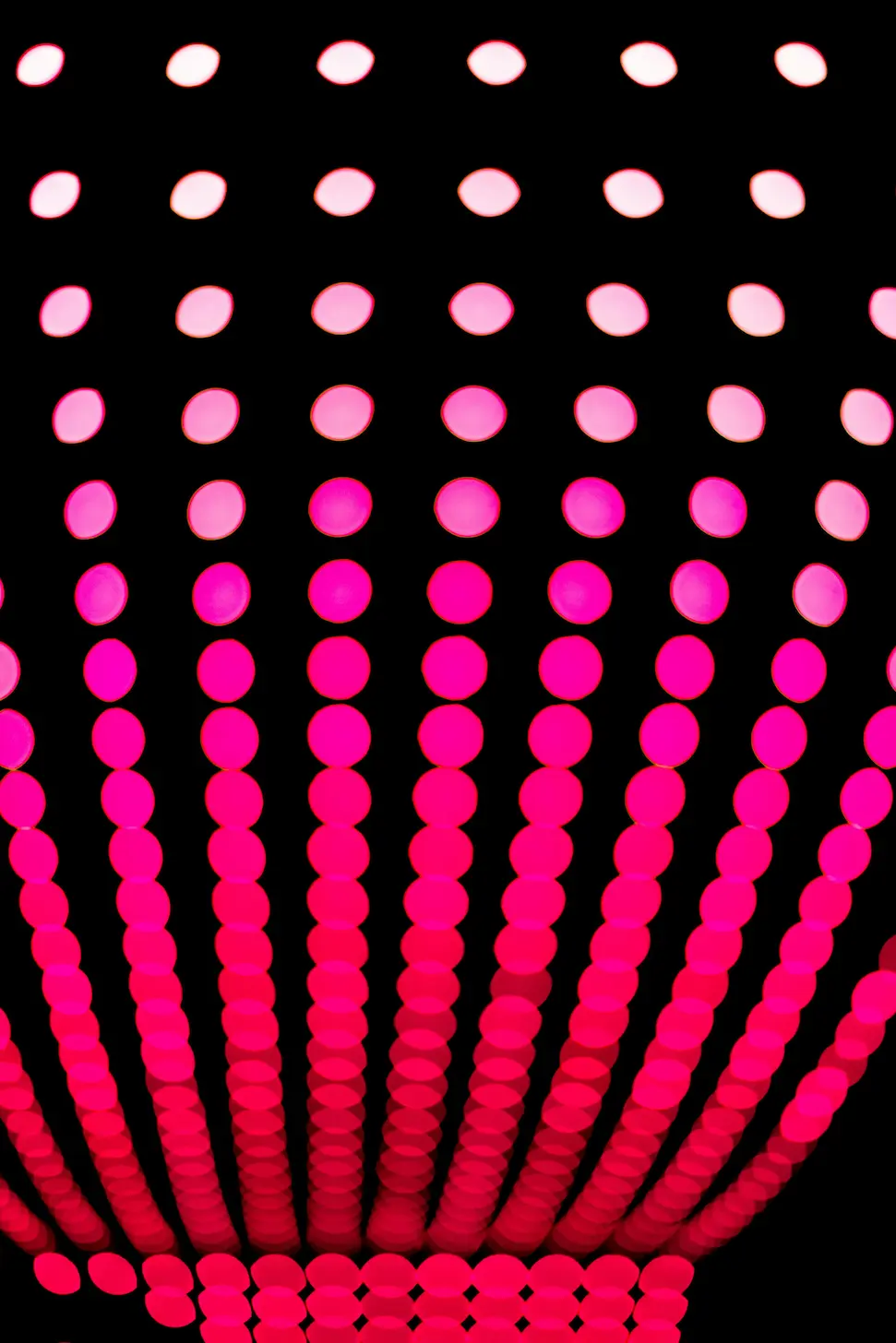 an unfocused shot of neon pink string lights at night.